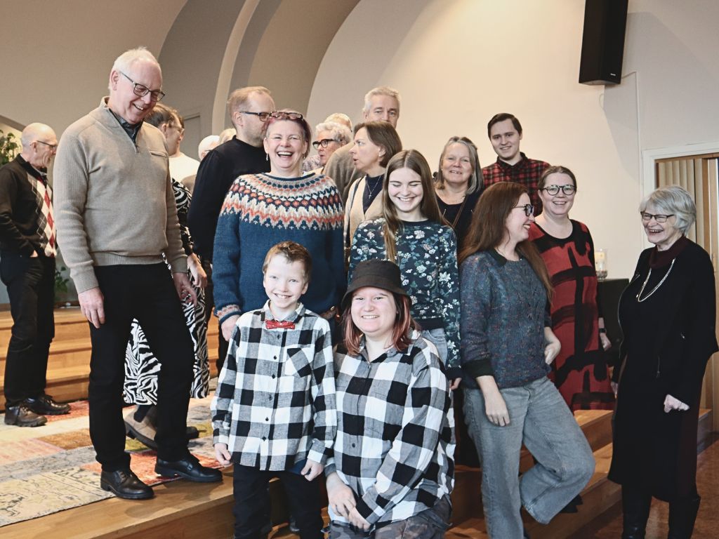En grupp människor på estraden i Pingstkyrkan Skillingaryd som ler och skrattar tillsammans.